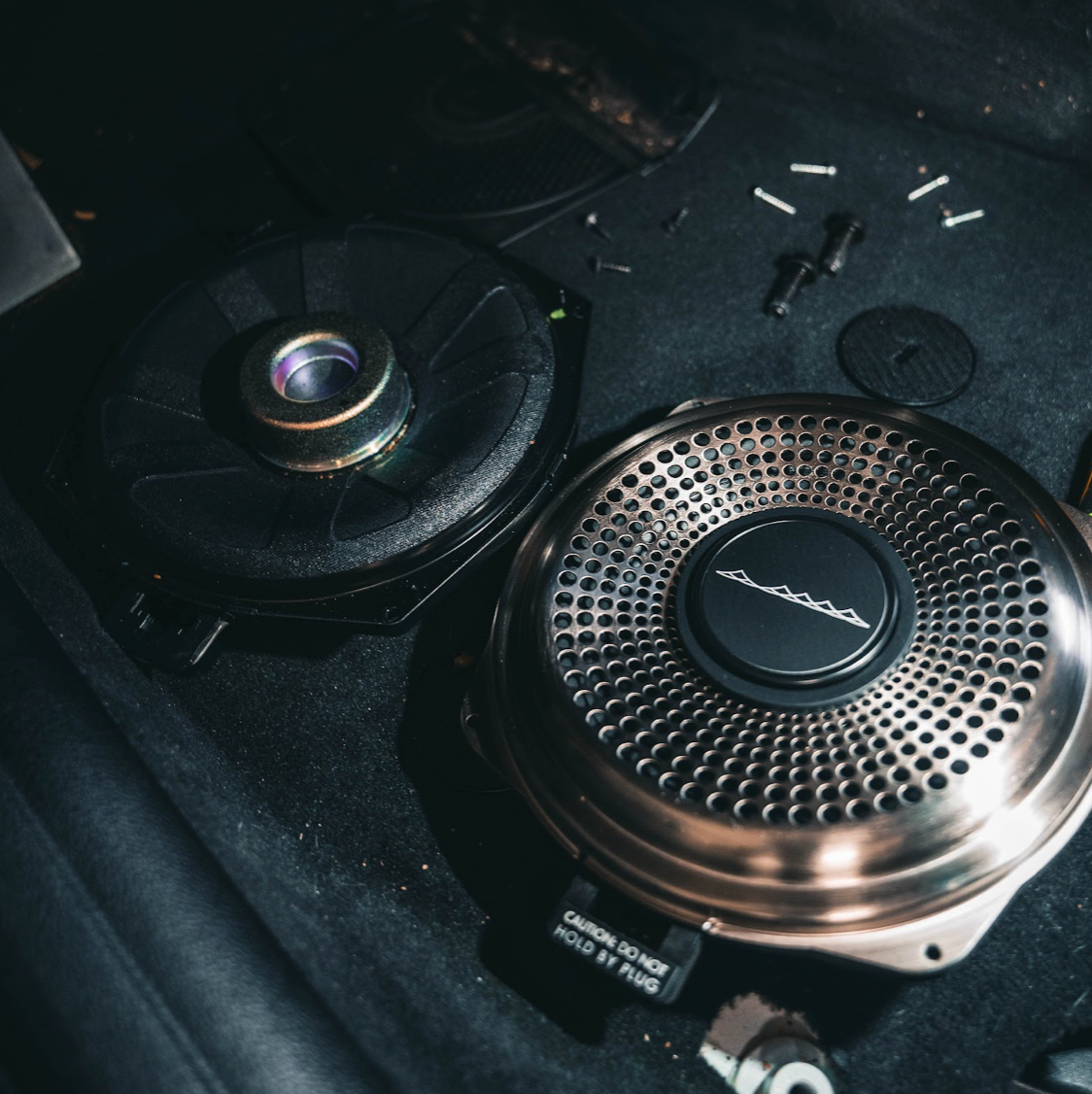 Photo of the quality material improvement of the Bavsound Ghost under seat subwoofer compared to the factory under seat subwoofer.